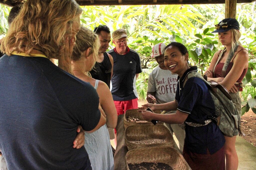 TrovaTrip travelers standing around baskets of coffee beans with locals