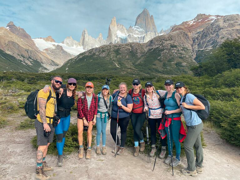 TrovaTrip travelers holding hiking gear with mountains behind them