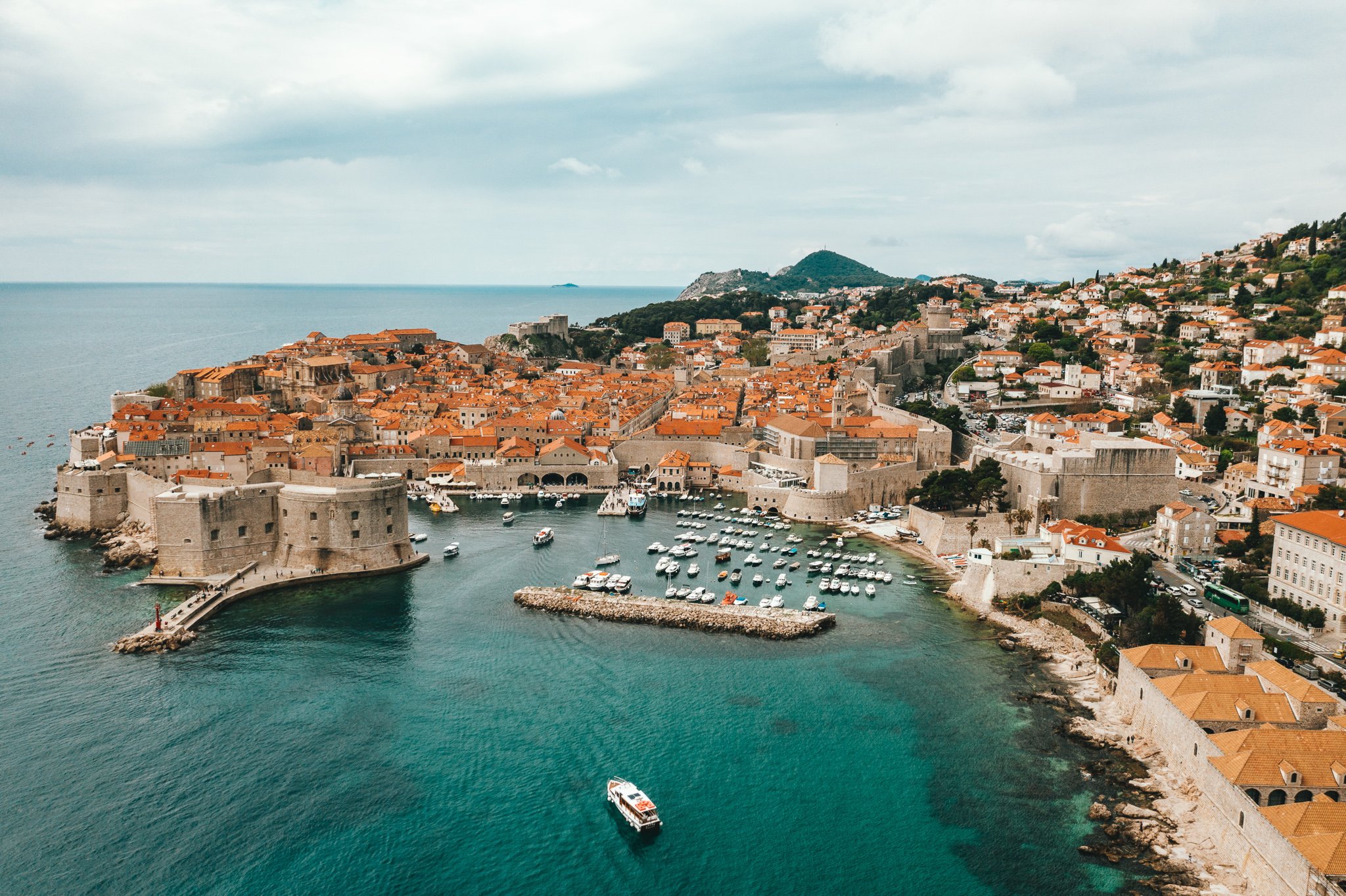 TrovaTrip view of Dubrovnik Croatia with houses on an island sitting on greenish blue waters with boats 