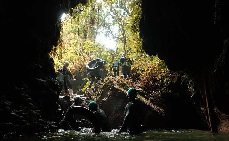 TrovaTrip travelers tubing through a river exiting from a cave in New Zealand