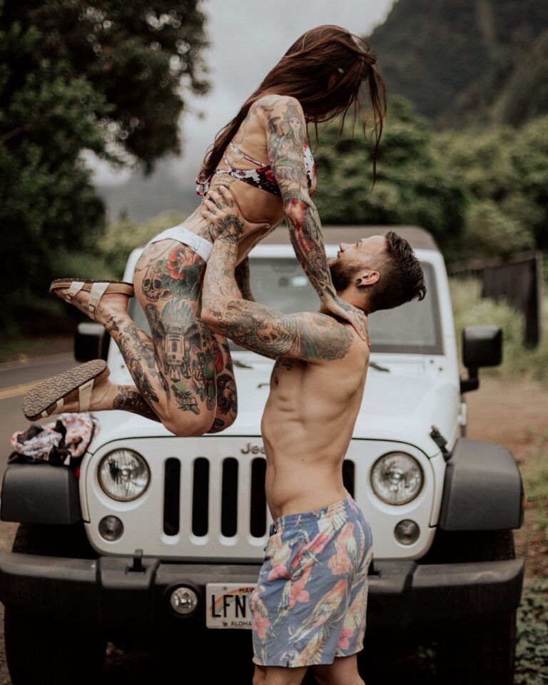 TrovaTrip a man with tattoos holding up a woman with tattoos in front of white jeep