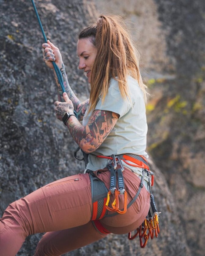 TrovaTrip woman with tattoos climbing a mountain with climbing gear