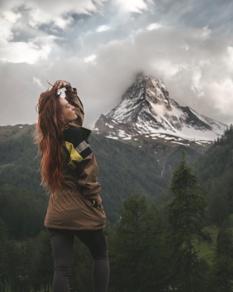 TrovaTrip woman standing in front of view of snowy mountain with her hand in her hair