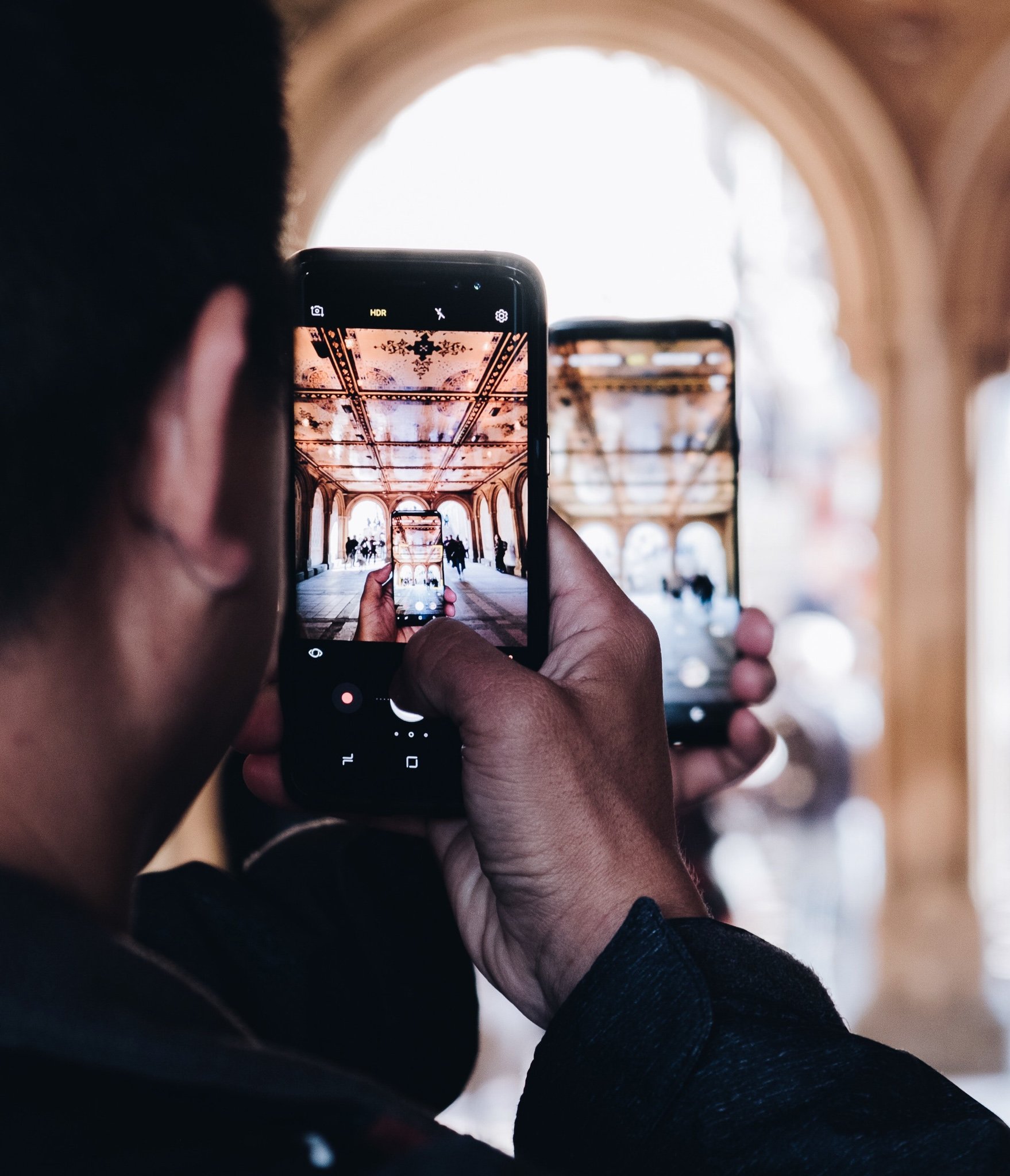 TrovaTrip man holding phone inside a monument taking a picture of his other hand holding a phone taking a picture