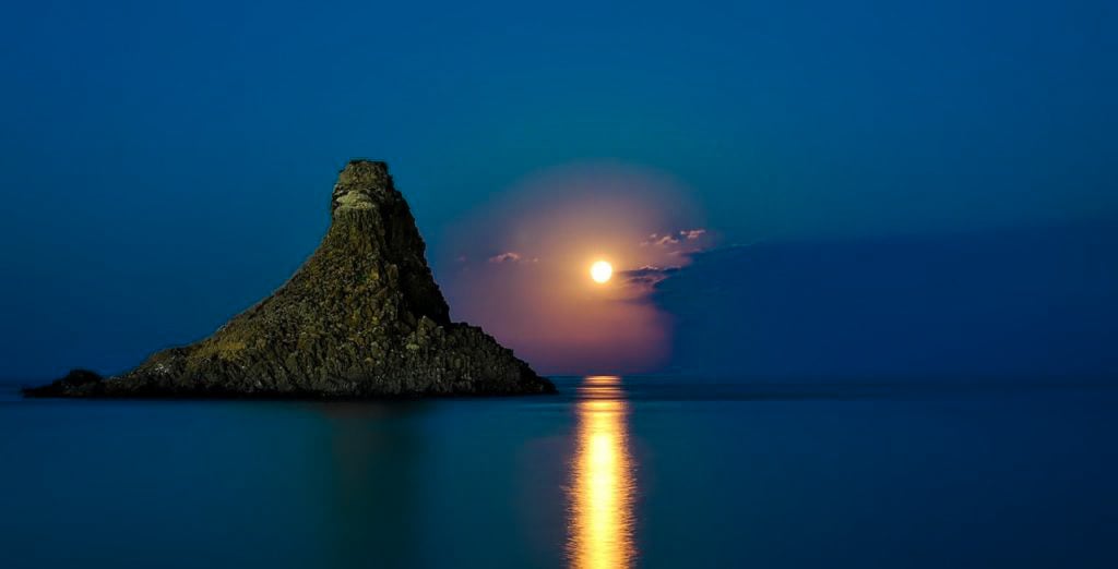 TrovaTrip sun setting behind dark blue waters with large mountain on an island in Sicily