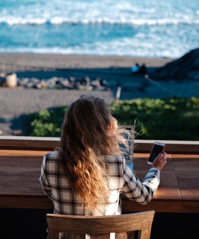 Person looking at their phone near the beach.
