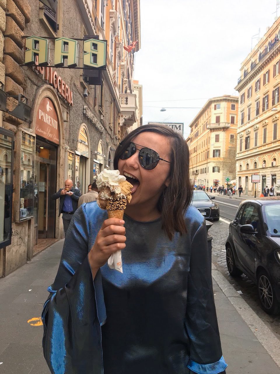 TrovaTrip traveler in black sunglasses eating gelato on a cone in Italy's sidewalks
