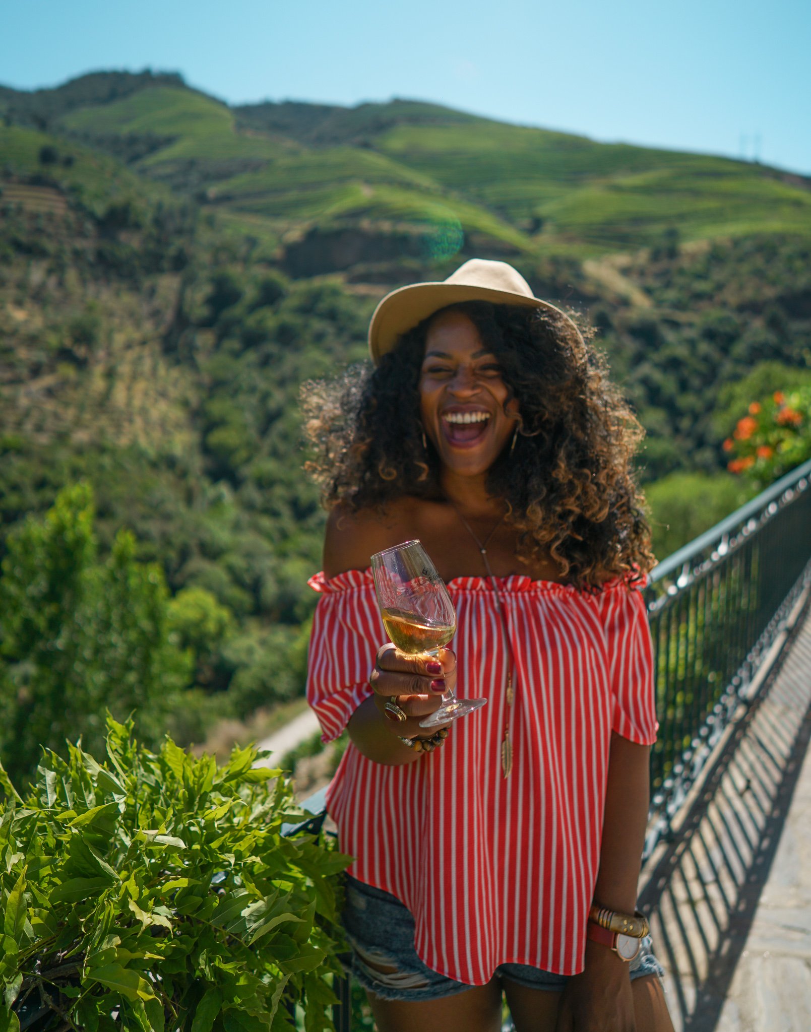 TrovaTrip woman in a hat holding a wine glass with Portugal hills behind her