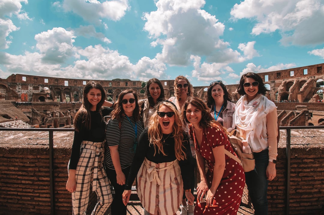 TrovaTrip group of travelers smiling in front of the Colosseum in Rome