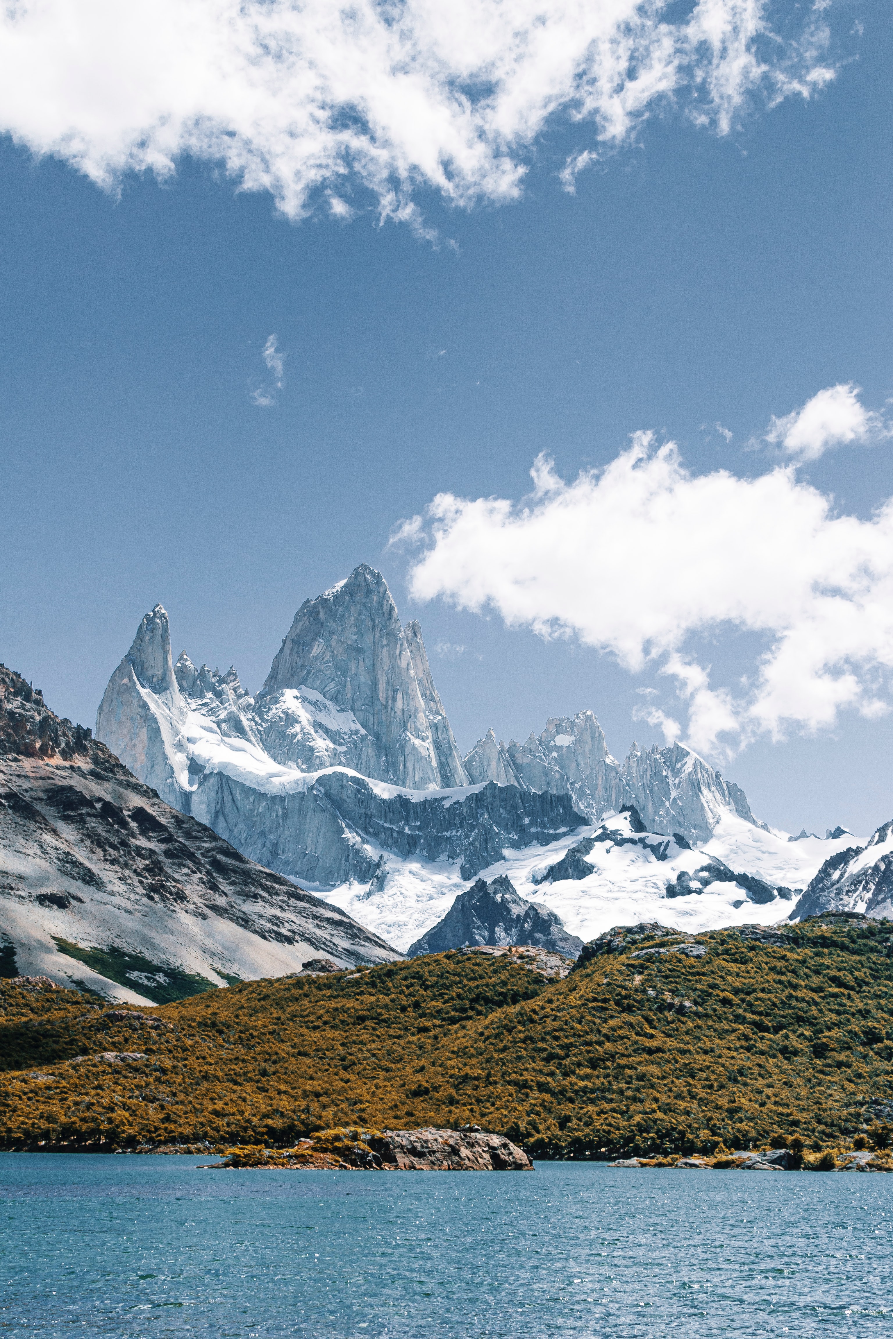 trovatrip El Chalten with clouds behind mountains against clear blue sky and clear blue waters in forefront