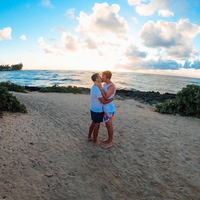 TrovaTrip two travelers kissing on the beach with sun setting behind the ocean