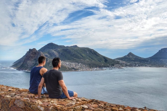 Couple sitting on a ledge of rocks looking out at the water and island in front of them