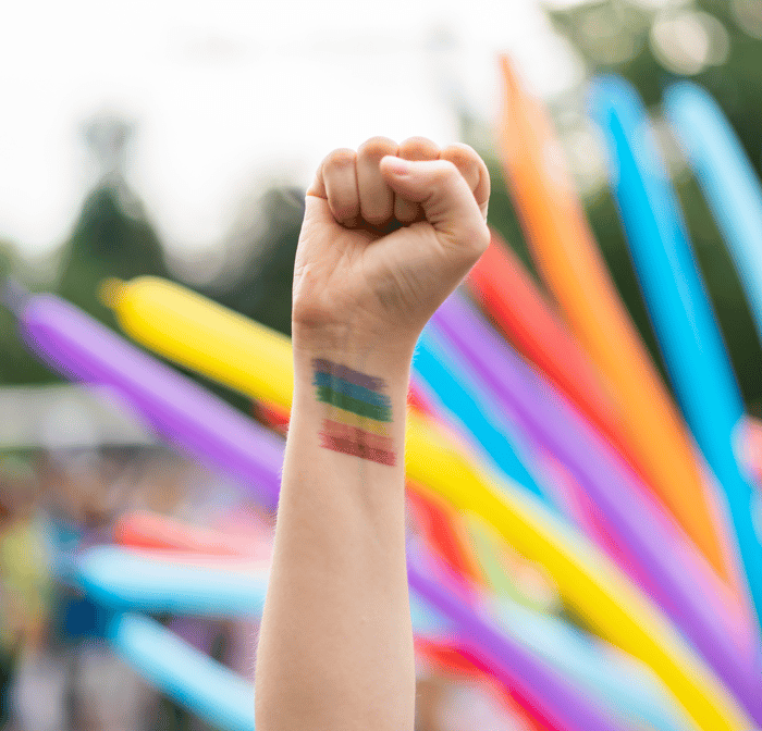 TrovaTrip fist being held up with pride flag painted on arm at festival