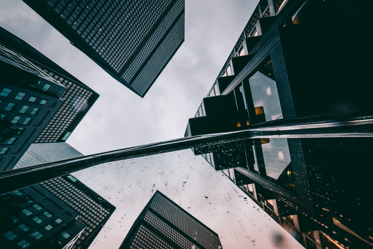 TrovaTrip pov from the ground looking up at several skyscrapers against a cloudy grey sky