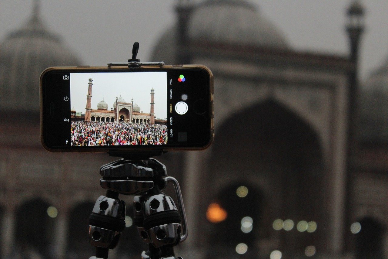 TrovaTrip cellphone on a tripod taking a picture of a festival of people in front of a large monument