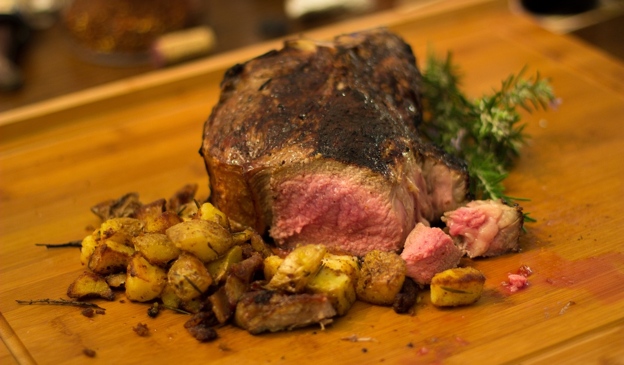 TrovaTrip Bistecca Fiorentina (Steak Florentine) cooked to perfection with a side of roasted potatoes on a wooden tray