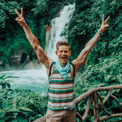 TrovaTrip Costa Rica man posing with peace signs in front of waterfall
