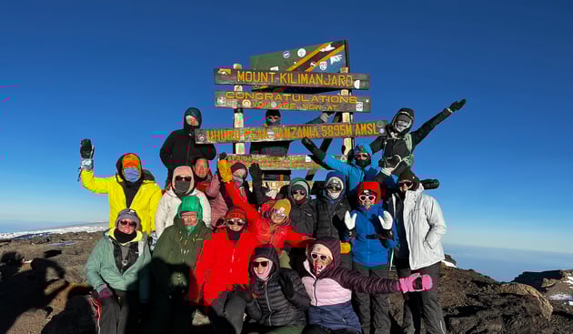 Group of women celebrating after summiting Mount Kilimanjaro–one of the best destinations to explore with Travel Groups for Women.