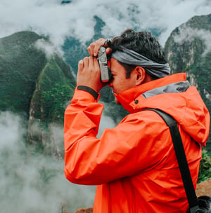 TrovaTrip Peru Traveler in orange jacket taking picture with camera