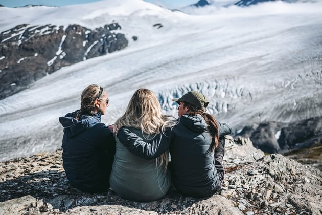 Three women hugging each other on a hiking trail in Alaska, on a trovatrip which are great solo vacation packages for solo travelers seeking adult friendship.