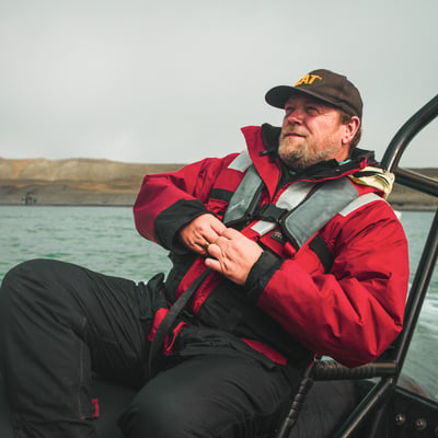 TrovaTrip man in red jacket and brown hat smiling on a boat