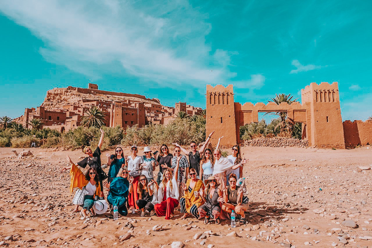 TrovaTrip Morocco group of travelers smiling at camera and posing in front of monument
