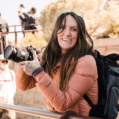 TrovaTrip Sedona woman with pale pink puffer jacket smiling holding camera