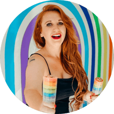 CEO and founder of EveryQueer, Meg Ten Eyck headshot with rainbow background.