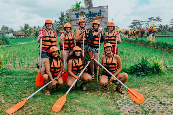 TrovaTrip Bali group of travelers in orange helmets and life jackets holding paddles