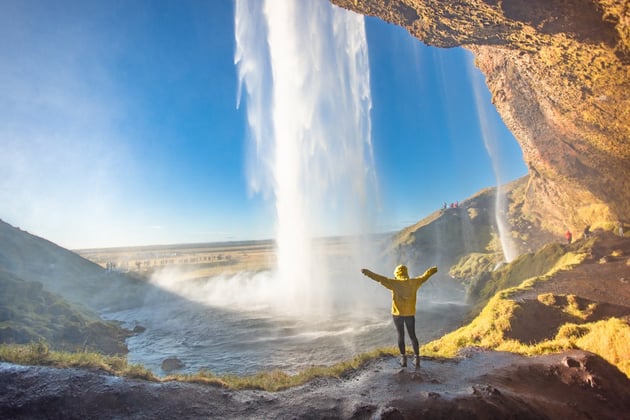 Person hiking at a waterfall in Iceland, one of the best places to solo travel.