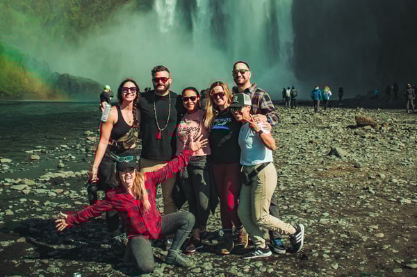 TrovaTrip Iceland group posing and smiling in front of waterfall