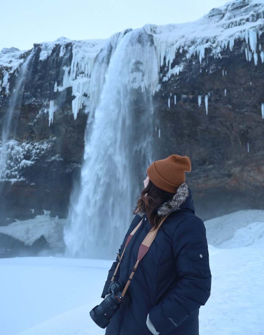 Traveler looking at a waterfall in Iceland, exploring 2026 group travel.