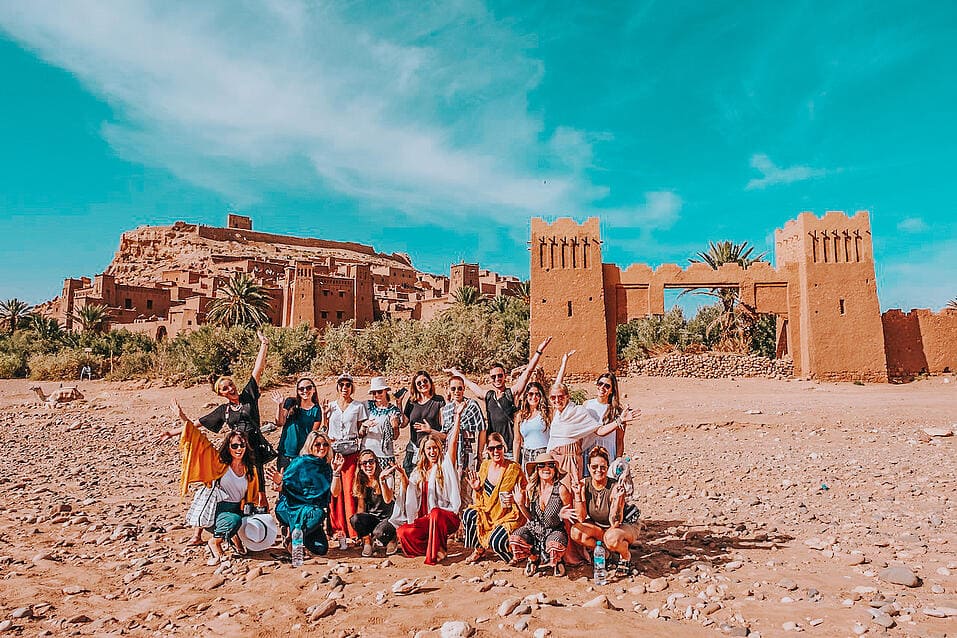 TrovaTrip Morocco group of travelers smiling at camera and posing in front of monument
