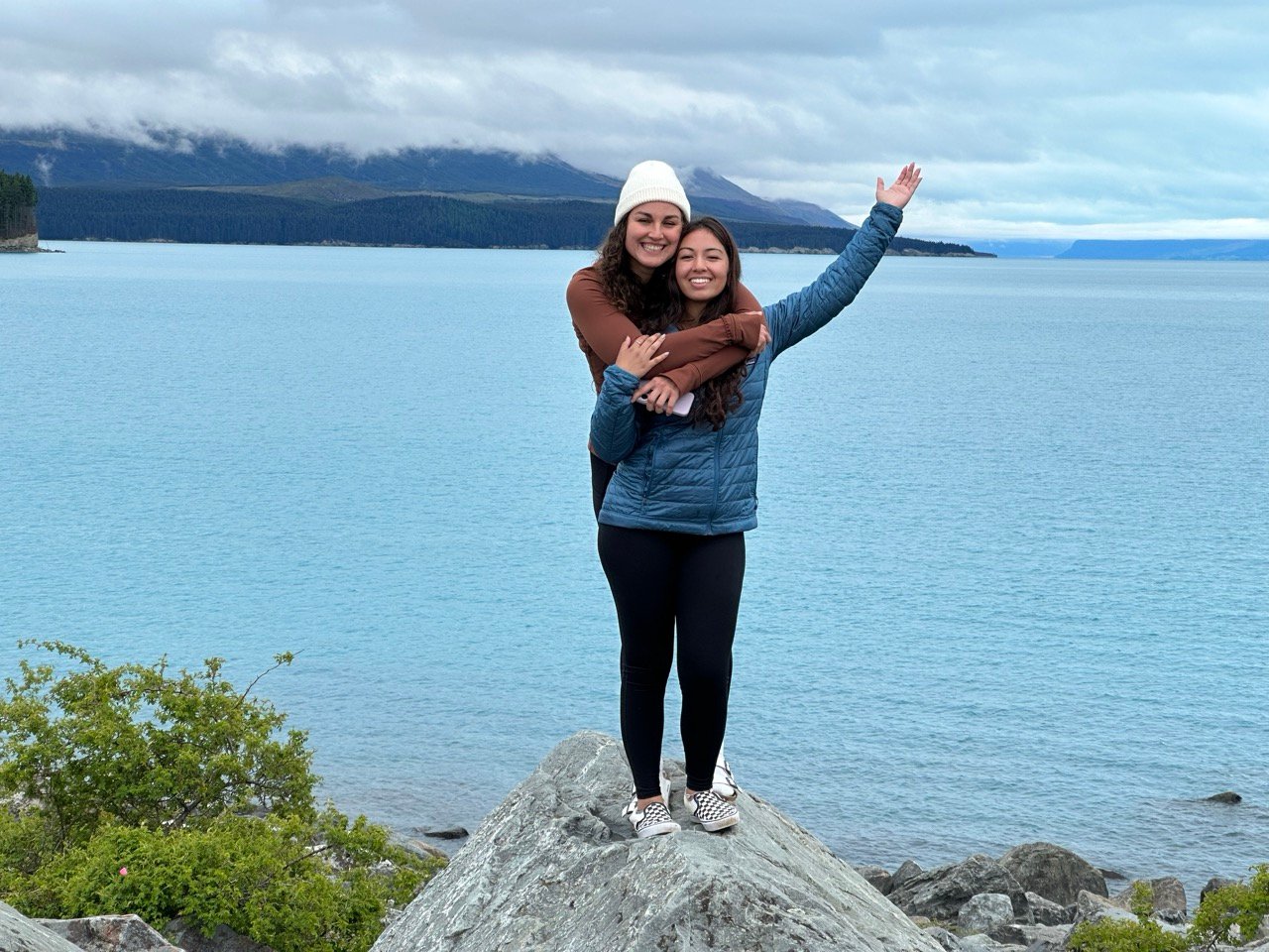 Friends hugging in New Zealand, a great place to visit in January.