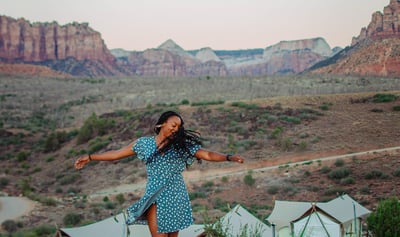 TrovaTrip Zion woman standing with arms extended out and mountains behind her
