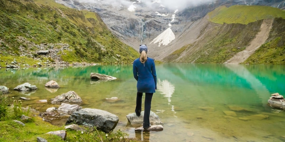  A traveler standing in front of Hummantay Lake in the Peruvian Andes.